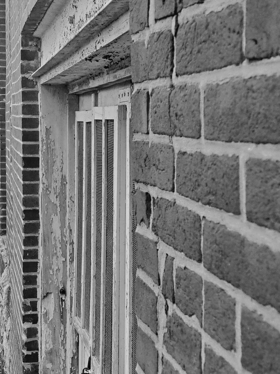 a black and white photo of a window on a brick building